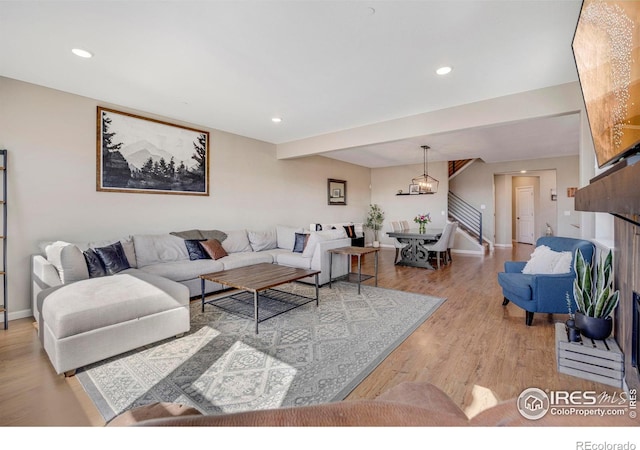 living room with light wood-type flooring, a notable chandelier, recessed lighting, baseboards, and stairs