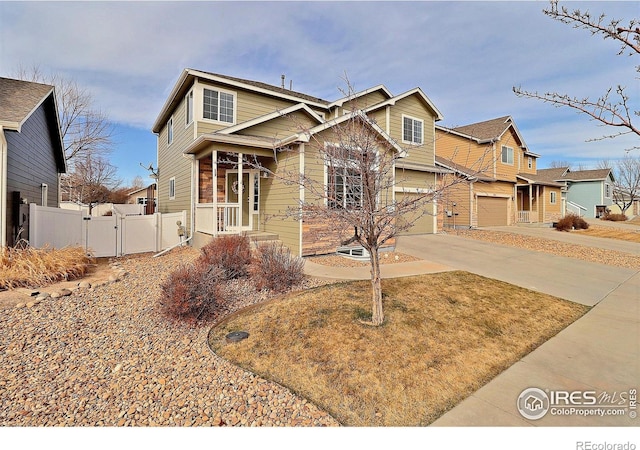 view of front of property featuring concrete driveway, a gate, fence, and an attached garage