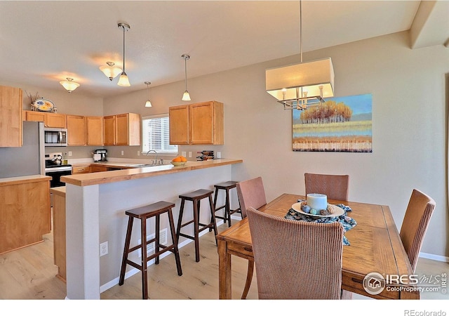 kitchen featuring stainless steel microwave, electric range, a peninsula, and light wood finished floors