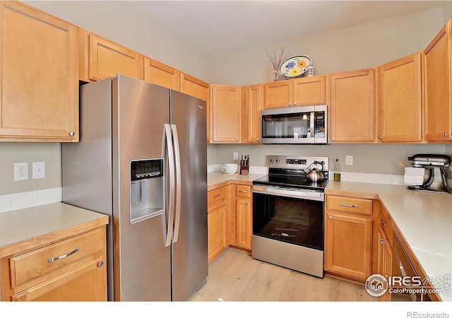 kitchen featuring light wood-type flooring, stainless steel appliances, light brown cabinets, and light countertops