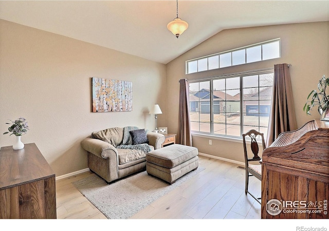 living area with baseboards, lofted ceiling, and wood finished floors