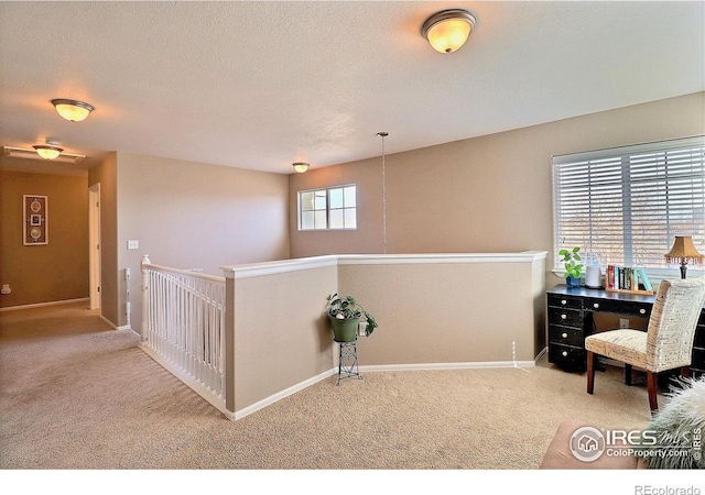 interior space featuring baseboards, an upstairs landing, a textured ceiling, and carpet floors