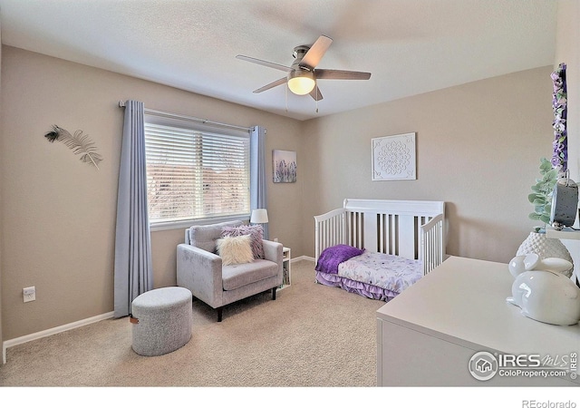 bedroom featuring a crib, carpet flooring, and baseboards