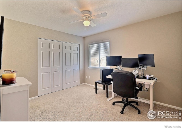 carpeted home office featuring baseboards, a textured ceiling, ceiling fan, and a textured wall