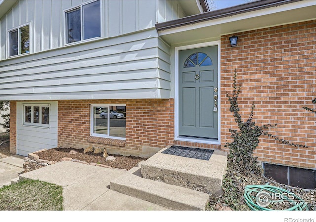 view of exterior entry with brick siding and board and batten siding