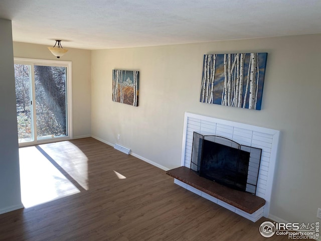 unfurnished living room with visible vents, baseboards, wood finished floors, and a fireplace