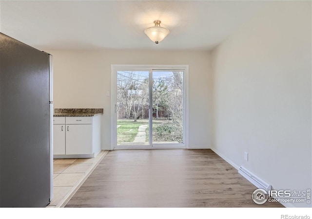 unfurnished dining area featuring baseboards and light wood finished floors