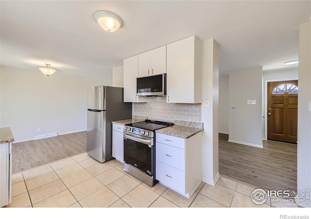 kitchen with visible vents, tasteful backsplash, white cabinetry, appliances with stainless steel finishes, and light tile patterned flooring