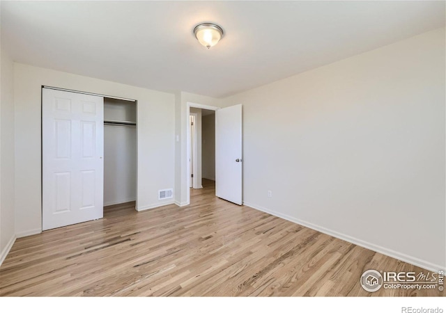 unfurnished bedroom featuring a closet, visible vents, baseboards, and light wood-style floors