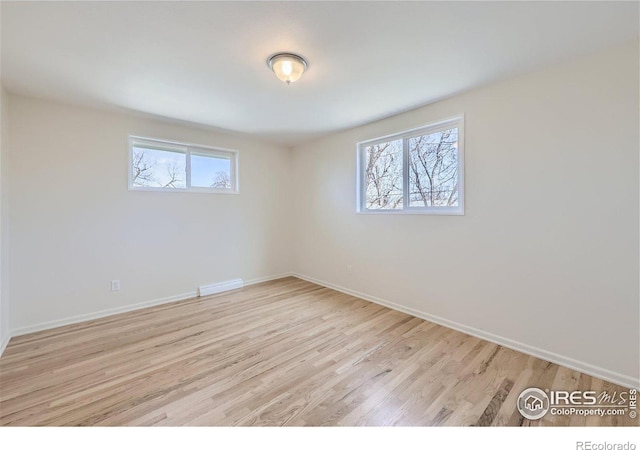 spare room featuring visible vents, baseboards, and light wood-style floors