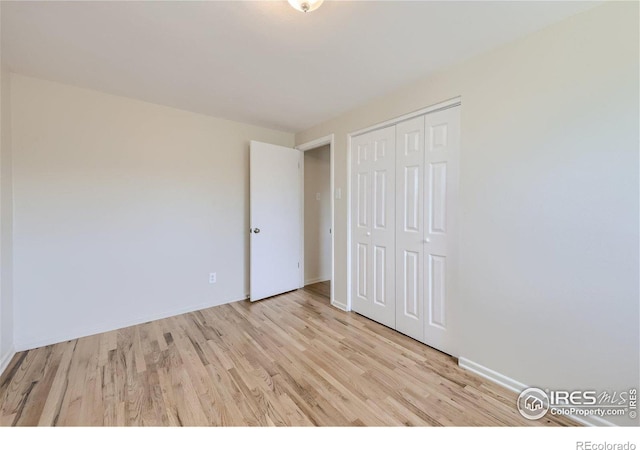 unfurnished bedroom with a closet, light wood-style flooring, and baseboards