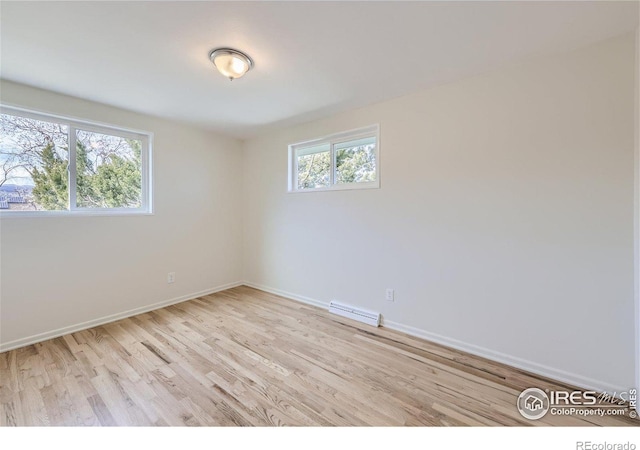 spare room featuring baseboards and light wood-style floors