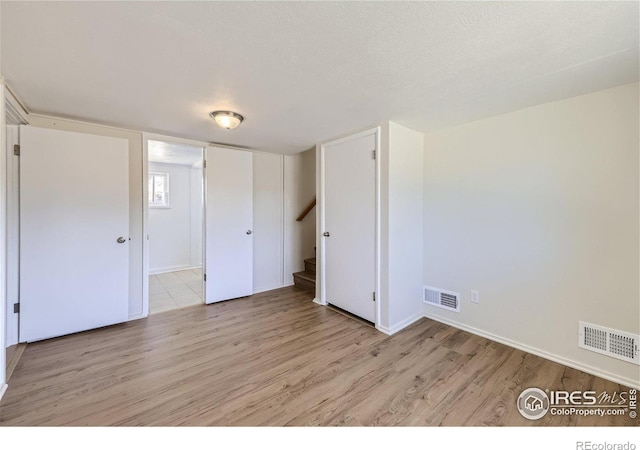 unfurnished bedroom with visible vents, light wood-style floors, and a textured ceiling