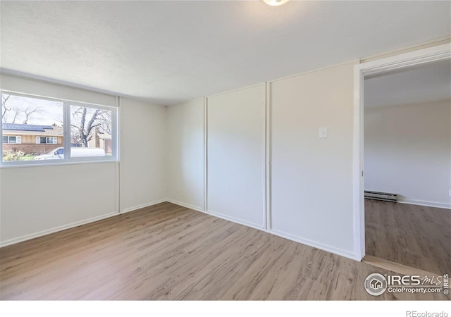 unfurnished bedroom featuring a baseboard radiator and wood finished floors