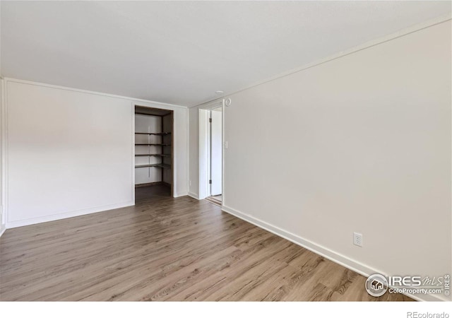 spare room with baseboards and wood finished floors