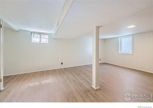 below grade area featuring a wealth of natural light, baseboards, and wood finished floors