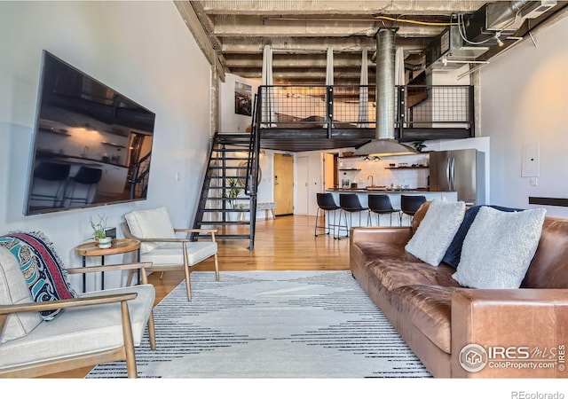 living area with stairway, a high ceiling, and wood finished floors