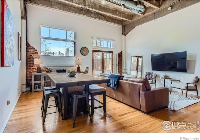 interior space featuring light wood-style flooring, french doors, baseboards, and a towering ceiling