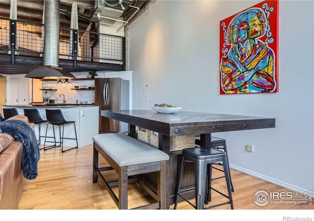 dining space with light wood-style floors, baseboards, and a high ceiling