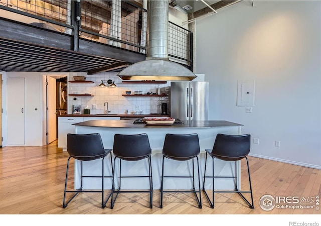 kitchen featuring dark countertops, open shelves, freestanding refrigerator, light wood-style floors, and a sink