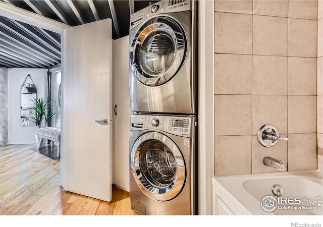 laundry area featuring stacked washer / dryer, laundry area, and light wood-style floors