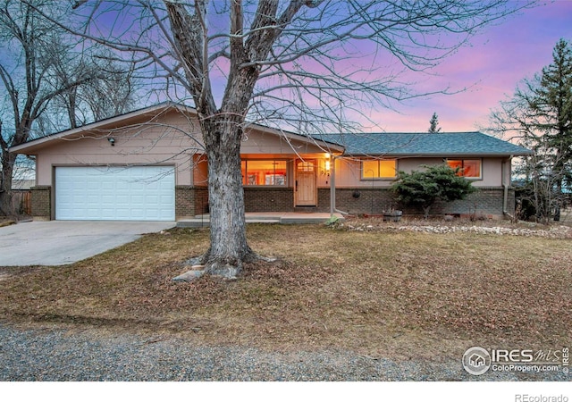 single story home with brick siding, covered porch, driveway, and an attached garage