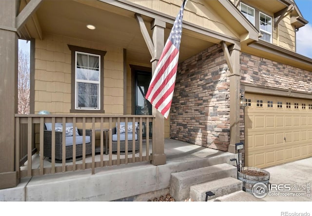 entrance to property with a porch, an attached garage, and stone siding