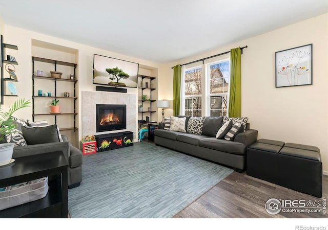 living area with a tile fireplace and wood finished floors