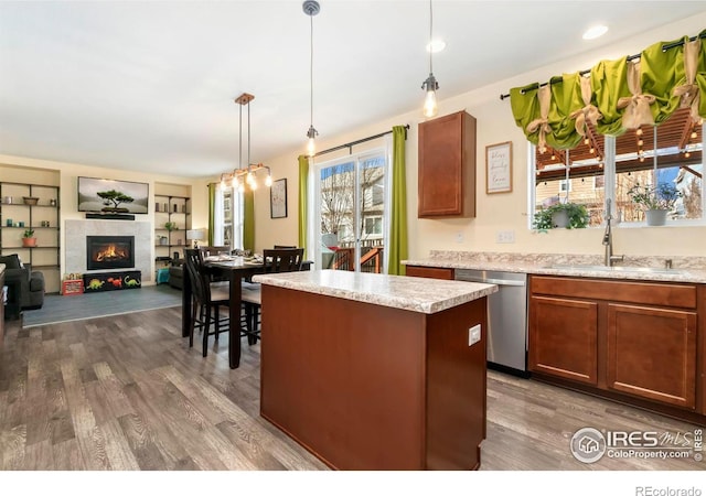 kitchen featuring a sink, stainless steel dishwasher, dark wood-style floors, and light countertops