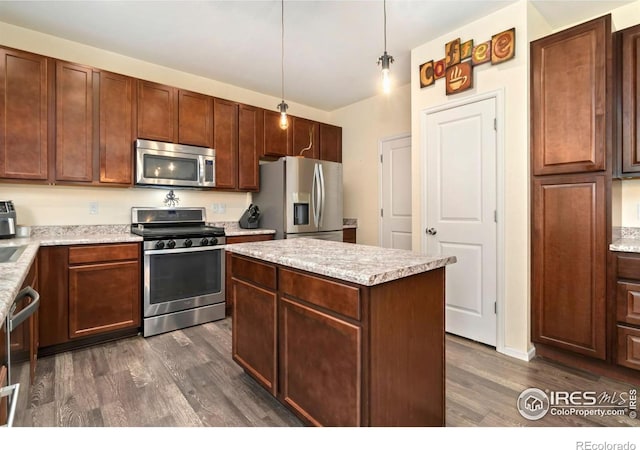 kitchen with dark wood-style floors, appliances with stainless steel finishes, a center island, and light countertops