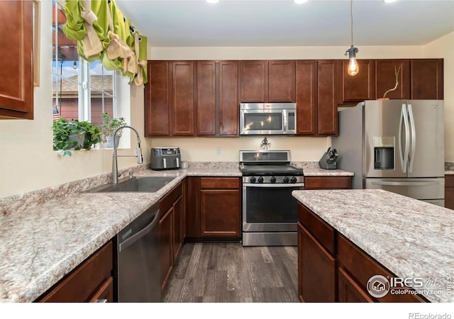 kitchen featuring hanging light fixtures, dark wood-style flooring, appliances with stainless steel finishes, and a sink