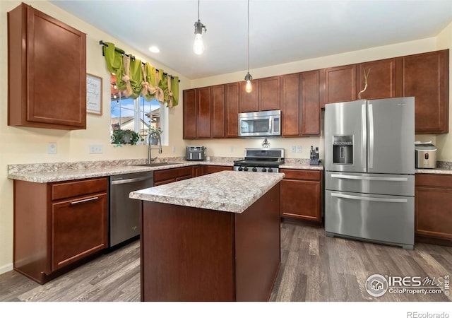 kitchen featuring dark wood-style floors, a kitchen island, a sink, stainless steel appliances, and light countertops