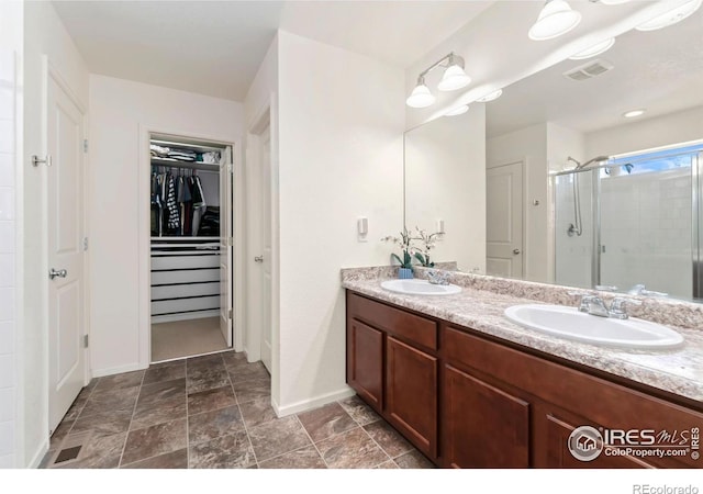 full bathroom featuring a walk in closet, a stall shower, visible vents, and a sink