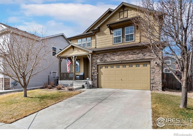 view of front of property featuring a front lawn, stone siding, covered porch, concrete driveway, and a garage