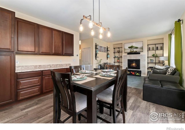 dining room featuring dark wood-style floors and a tiled fireplace