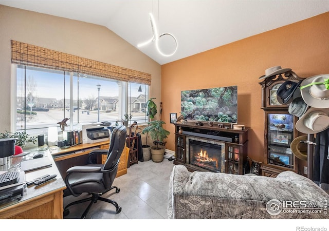 office area featuring a glass covered fireplace and lofted ceiling