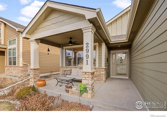 property entrance with stone siding, covered porch, board and batten siding, and a ceiling fan