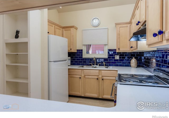 kitchen with light brown cabinets, a sink, under cabinet range hood, freestanding refrigerator, and light countertops