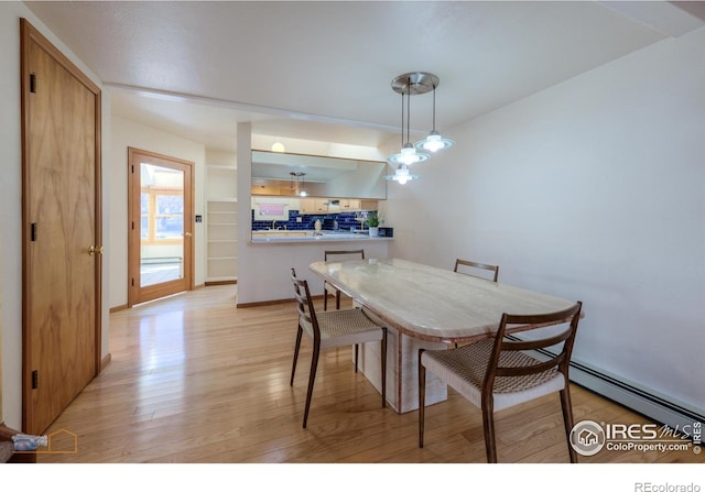 dining area with baseboards, baseboard heating, and light wood finished floors