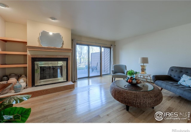 living area with wood finished floors and a glass covered fireplace