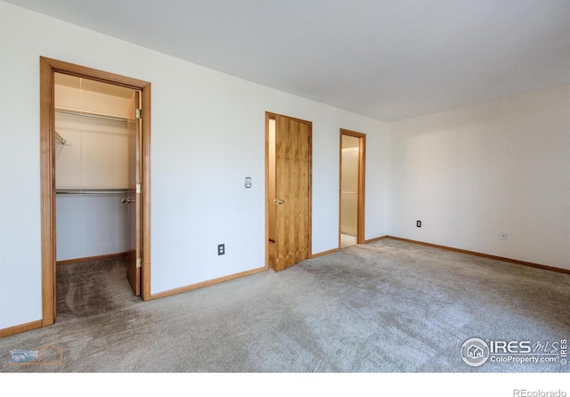 unfurnished bedroom with a spacious closet, carpet flooring, and baseboards