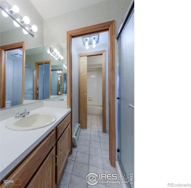 full bath with vanity, a shower with shower door, a baseboard radiator, tile patterned flooring, and toilet