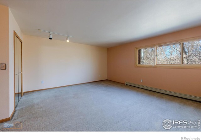 unfurnished room featuring rail lighting, baseboards, baseboard heating, and carpet flooring