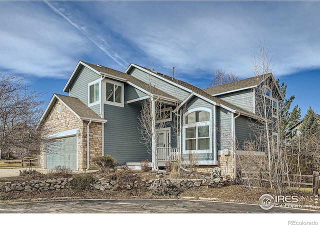 view of front of house with stone siding, driveway, and a garage