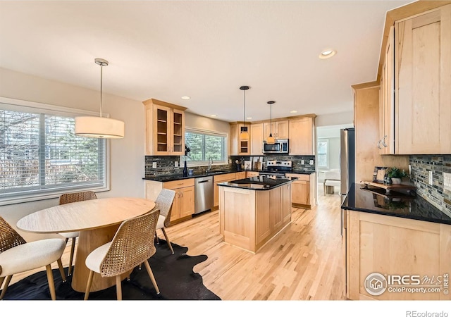 kitchen featuring stainless steel appliances, dark countertops, and light brown cabinetry