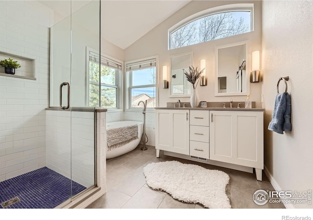 bathroom with double vanity, a freestanding bath, a stall shower, and a sink