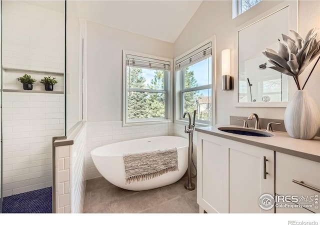 full bathroom with a freestanding tub, a walk in shower, tile walls, tile patterned flooring, and vanity