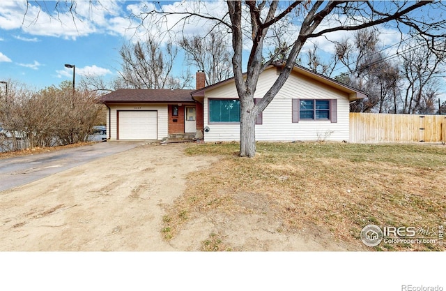 ranch-style home with a front lawn, fence, concrete driveway, a garage, and a chimney