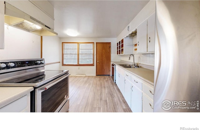 kitchen with under cabinet range hood, a sink, tasteful backsplash, stainless steel appliances, and white cabinets