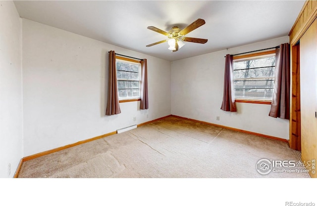 unfurnished room with a baseboard heating unit, ceiling fan, baseboards, and light carpet